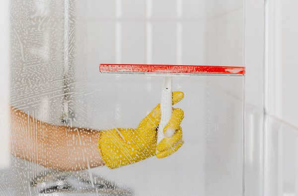 main avec gant jaune qui nettoie une vitre