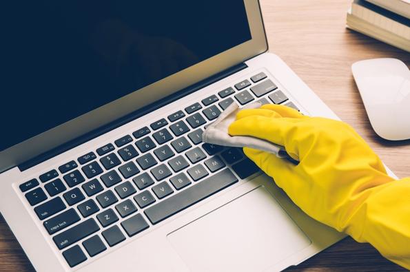 main qui nettoie un clavier d'ordinateur portable