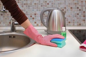 femme qui nettoie la cuisine avec une éponge et gant
