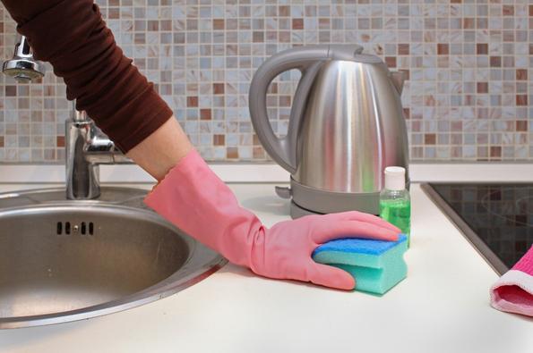femme qui nettoie la cuisine avec une éponge et gant