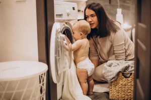 femme avec un bébé devant une machine à laver