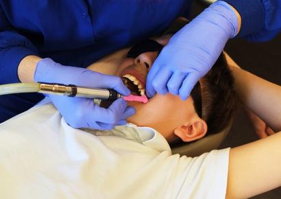 dentiste qui nettoie les dents d'un enfant 