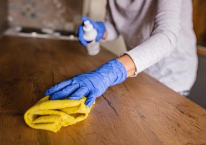 femme qui nettoie une table en bois avec une frange jaune
