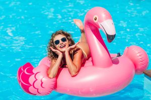 Femme blonde allongée sur une bouée flamant rose