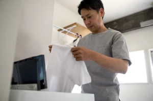homme qui mets un tshirt dans une machine à laver