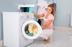 femme qui mets du linge dans la machine à laver