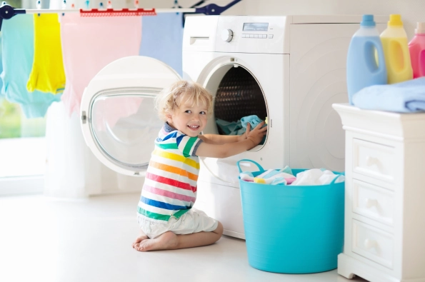 enfant qui mets du linge dans la machine à laver