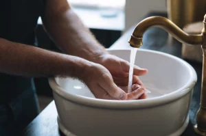 personne qui se lave les mains dans un lavabo