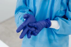 personne dans le milieu hospitalié qui porte une blouse et des gants