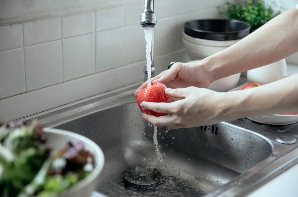 femme qui lave une pomme dans une cuisine