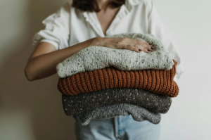 femme qui tient des pulls pliés